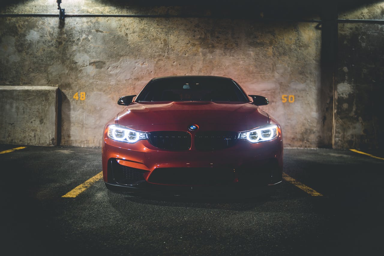 hero-img-02 A luxury red car parked in a dimly lit garage showcasing its sleek design and bright headlights.
